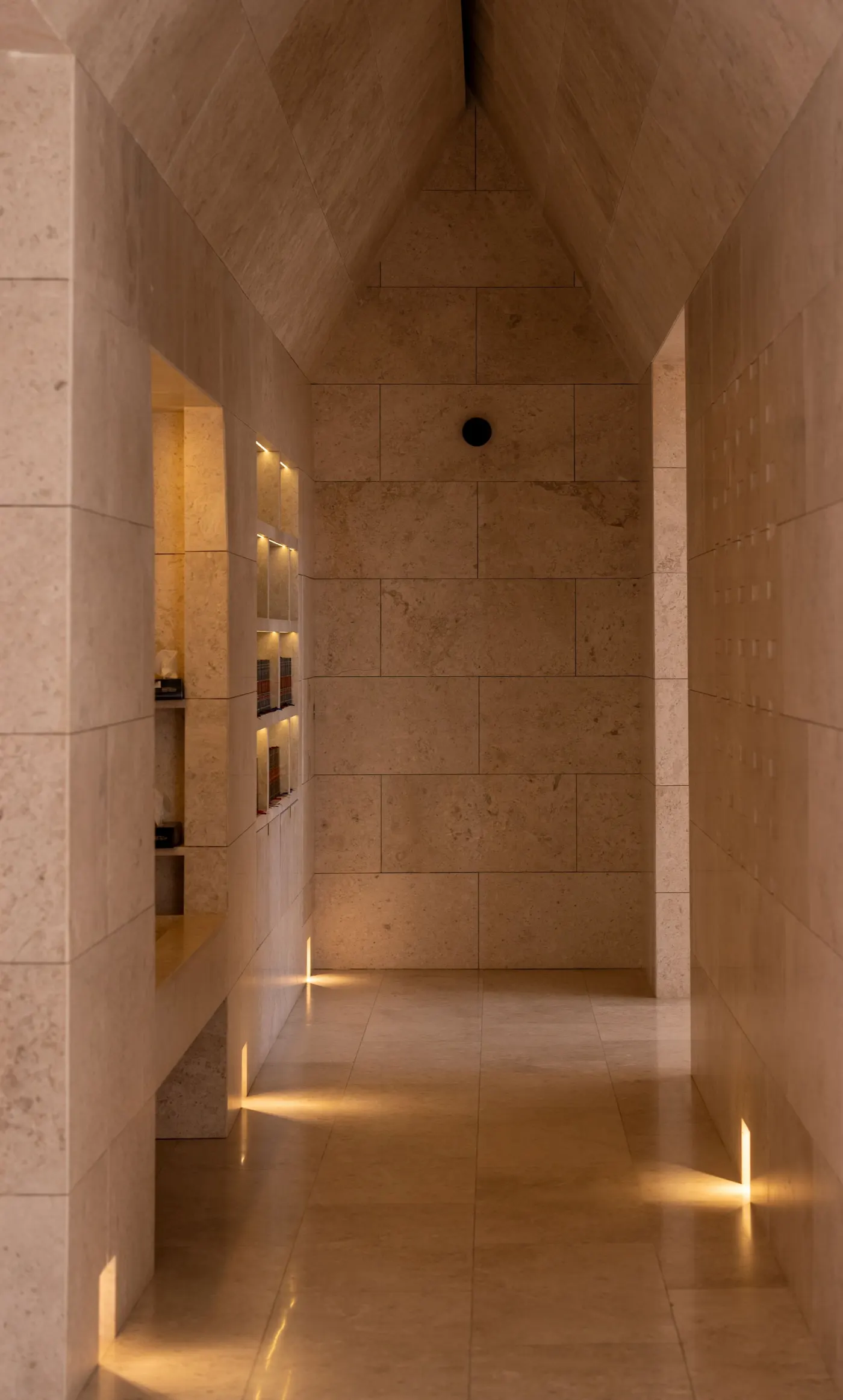 A warmly lit stone hallway with recessed lighting