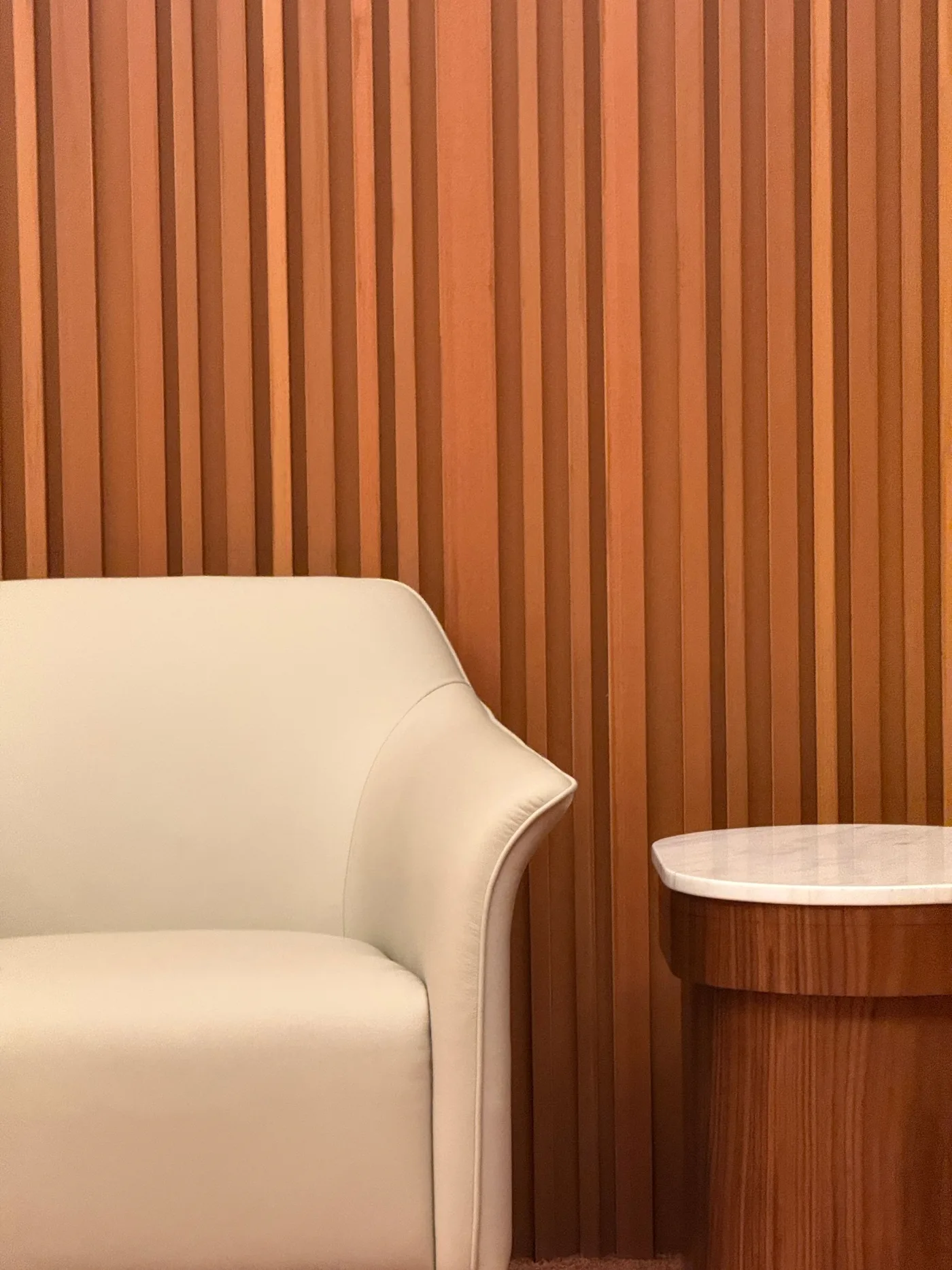 A cream armchair against a fluted timber wall